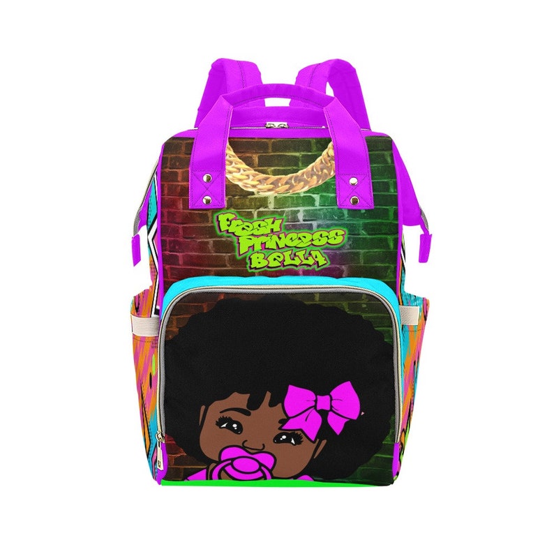 May include: A purple and multi-colored diaper bag with the text "Fresh Princess Bella". The bag features a cartoon image of a baby girl with a pacifier and a pink bow. The bag has multiple pockets and a top handle.