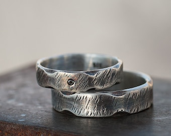 May include: Two silver rings with a textured finish. The top ring has a small black diamond in the center.