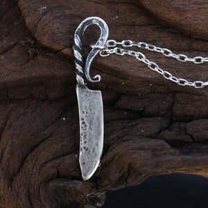 May include: A silver knife pendant necklace with a twisted handle and a chain.
