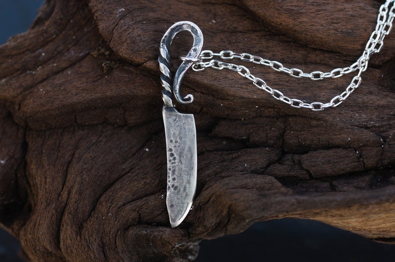 May include: A silver knife pendant necklace with a twisted handle and a chain.