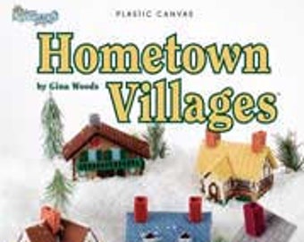 May include: A plastic canvas craft kit featuring 14 pieces to create a charming village. The kit includes 6 pieces with removable tops for storing goodies and treats. The image shows five different houses in various colors, including red, blue, yellow, and green.