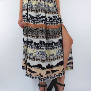 May include: A long, flowing maxi skirt with a black, white, and brown print of animals and trees. The skirt has a side slit and a black waistband.