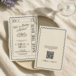May include: Two cream wedding save-the-date cards with black text and a decorative border. The cards read "We're Getting Married!" and "Save the Date" with the names Camille & Diego and the date July 22. A sprig of lavender and a glass of water are in the background.