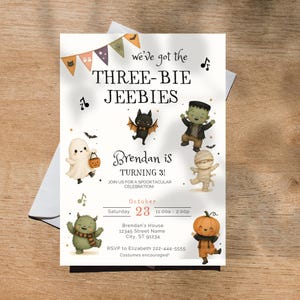 以下が含まれることがあります： 「we've got the THREE-BIE JEEBIES」および「Brendan is TURNING 3!」というテキストが記載された、ハロウィーンをテーマにした長方形の誕生日招待状。幽霊、コウモリ、フランケンシュタインの怪物、ミイラ、モンスター、カボチャのイラストが描かれています。