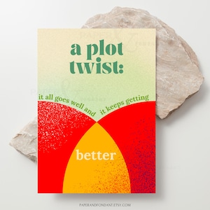 May include: A rectangular art print with the words "a plot twist:" in green, above the phrases "it all goes well and" and "it keeps getting" in green. The bottom half features red and yellow overlapping shapes, with the word "better" in white.