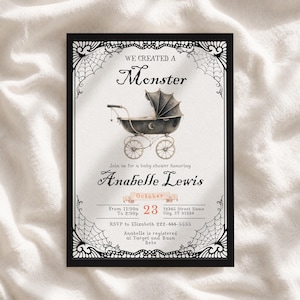 May include: A rectangular baby shower invitation card featuring a black spiderweb border and a central illustration of a vintage-style black baby carriage with a crescent moon. The text reads WE CREATED A Monster, Anabelle Lewis, October 23, and details.