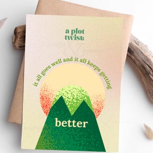 May include: Greeting card with a mountain illustration and the words "a plot twist" and "it all goes well and it all keeps getting better". The card has a beige background and is inside a brown envelope.
