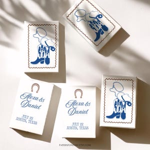 May include: White boxes with a cowboy boot and hat design in blue, with a brown border. Some boxes feature the names "Alexa & Daniel", the date "JULY 22", and the location "AUSTIN, TEXAS".