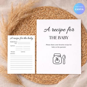 Può includere: Due biglietti di ricette bianchi con testo nero su sfondo tessuto. Il biglietto più grande recita "A recipe for THE BABY" e include una grafica di barattolo e cucchiaio. Il biglietto più piccolo dice "A recipe for the baby" con campi da compilare.