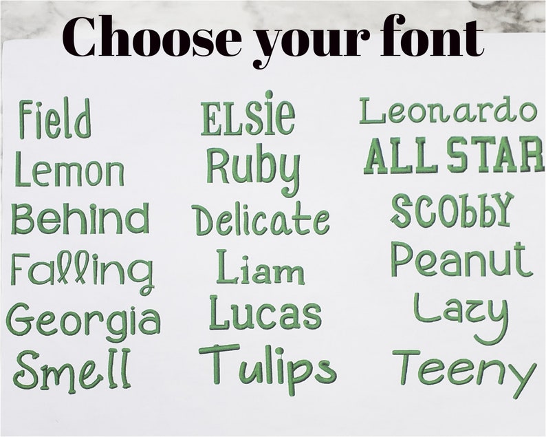 May include: A white display sheet featuring the black text Choose your font at the top, followed by three columns of green embroidered-style text samples including Field, Lemon, Behind, Falling, Georgia, Smell, ELSIE, Ruby, Delicate, Liam, Lucas, Tulips, Leonardo, ALL STAR, SCOBBY, Peanut, Lazy, and Teeny.