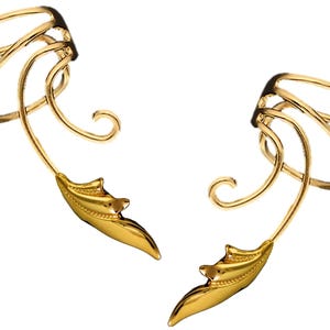 May include: A pair of gold ear cuffs with a leaf design. The cuffs are made of metal and have a delicate, intricate design.