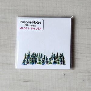 May include: A pack of Post-it® Notes with a watercolor illustration of a forest on the front. The pack contains 50 sheets and is made in the USA.