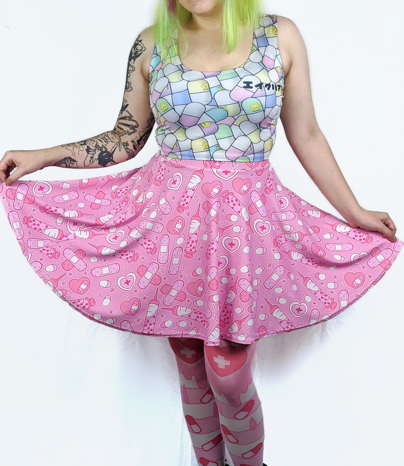 Pode incluir: Uma saia skater rosa com uma estampa de cora&ccedil;&otilde;es, bandagens, p&iacute;lulas e seringas. A saia &eacute; usada com meias rosa e brancas com uma estampa semelhante.