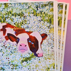 Peut inclure: Une peinture d'une vache brune et blanche aux yeux bleus allong&eacute;e dans un champ de fleurs blanches. La vache regarde le spectateur avec une expression curieuse.