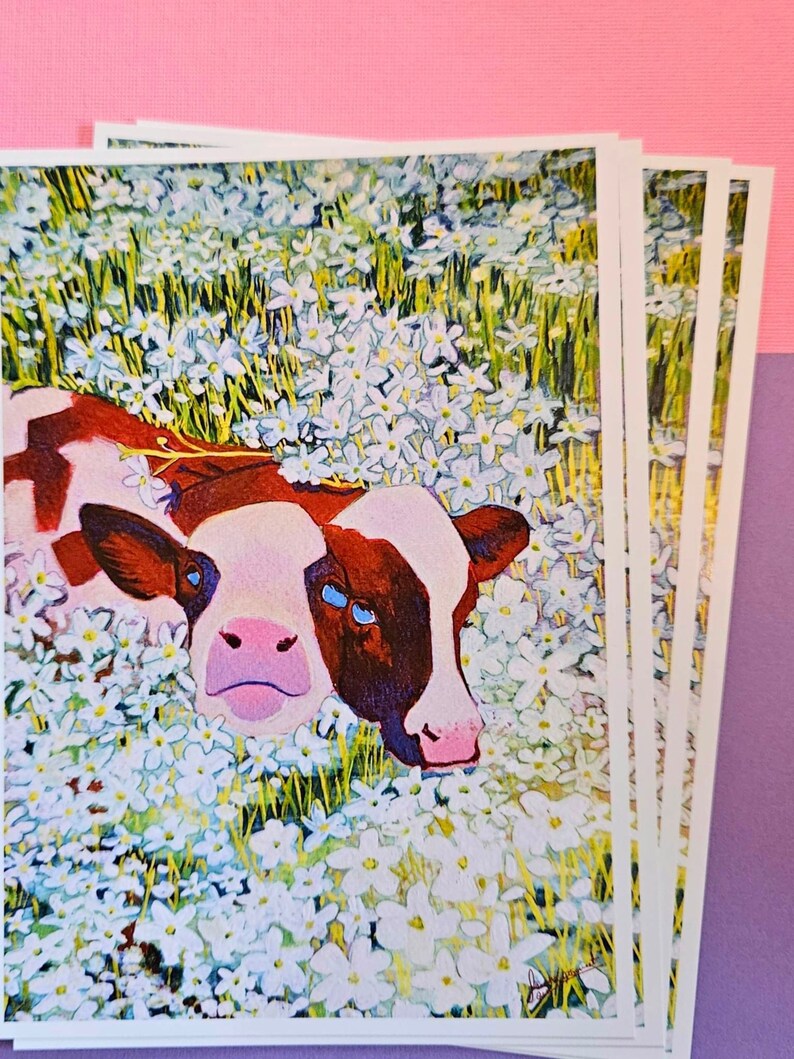 Peut inclure: Une peinture d'une vache brune et blanche aux yeux bleus allong&eacute;e dans un champ de fleurs blanches. La vache regarde le spectateur avec une expression curieuse.