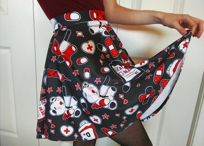 May include: A black skater skirt with a white and red print of teddy bears with bandages, hearts, stars, and pills. The text "Take Deads" is on a white checklist.
