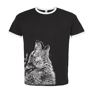 May include: Black t-shirt with a white ringer and a white wolf howling on the front. The wolf is in profile and the text "Corey Coulter" is written on the side of the wolf's face.