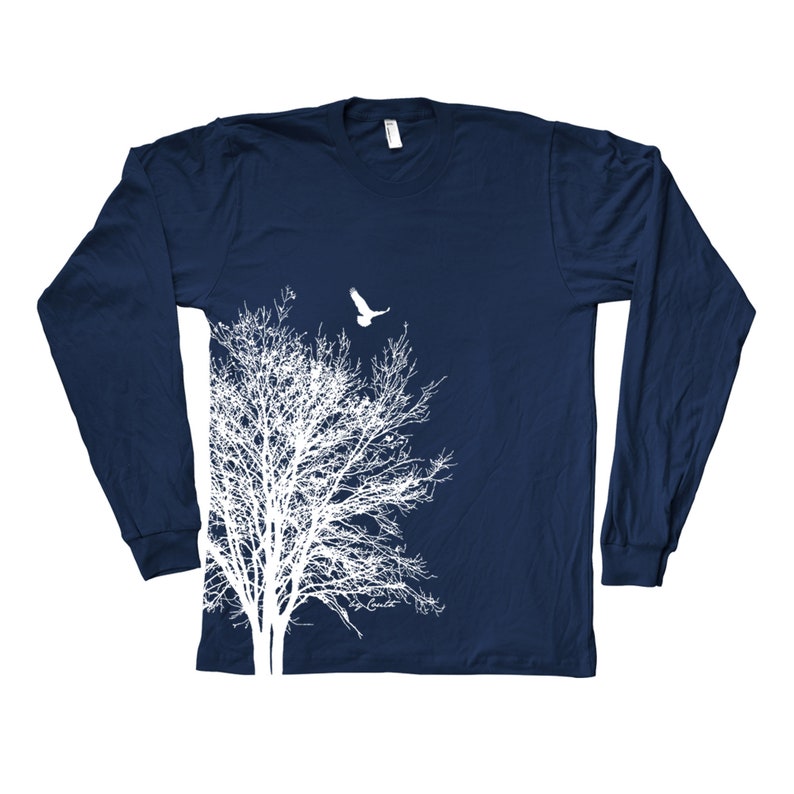 May include: A navy blue long-sleeved t-shirt featuring a white silhouette of a tree and a bird flying above it.