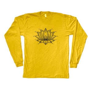 May include: Mustard yellow long-sleeved shirt with a black lotus flower design on the front. The lotus flower is detailed with intricate lines and dots. The shirt has a crew neck and long sleeves.