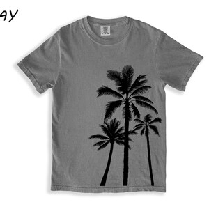 K&ouml;nnte beinhalten: Graues Kurzarm-T-Shirt mit schwarzem Palmen-Motiv. Das Wort "GRAY" ist in Schwarz in der oberen linken Ecke aufgedruckt. Das Shirt besteht aus einem weichen Material.