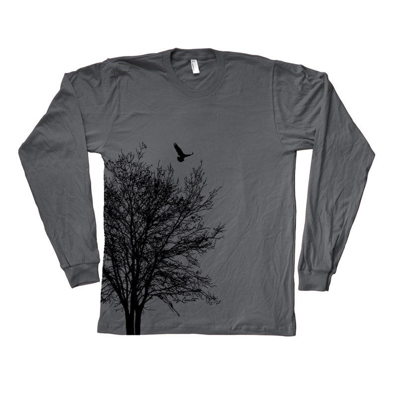 May include: A charcoal grey long-sleeved t-shirt featuring a black silhouette of a tree and a bird flying above it. The design is on the left side of the shirt.