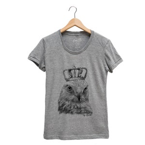 May include: A heather grey t-shirt with a black and white illustration of a hawk wearing a crown. The text "by Coult" is printed below the illustration.