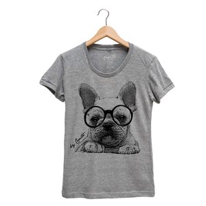 K&ouml;nnte beinhalten: Graues T-Shirt mit einer schwarz-wei&szlig;en Illustration eines franz&ouml;sischen Bulldoggen, der eine runde Brille tr&auml;gt. Der Text "by Coult" ist unten links auf dem Shirt gedruckt.