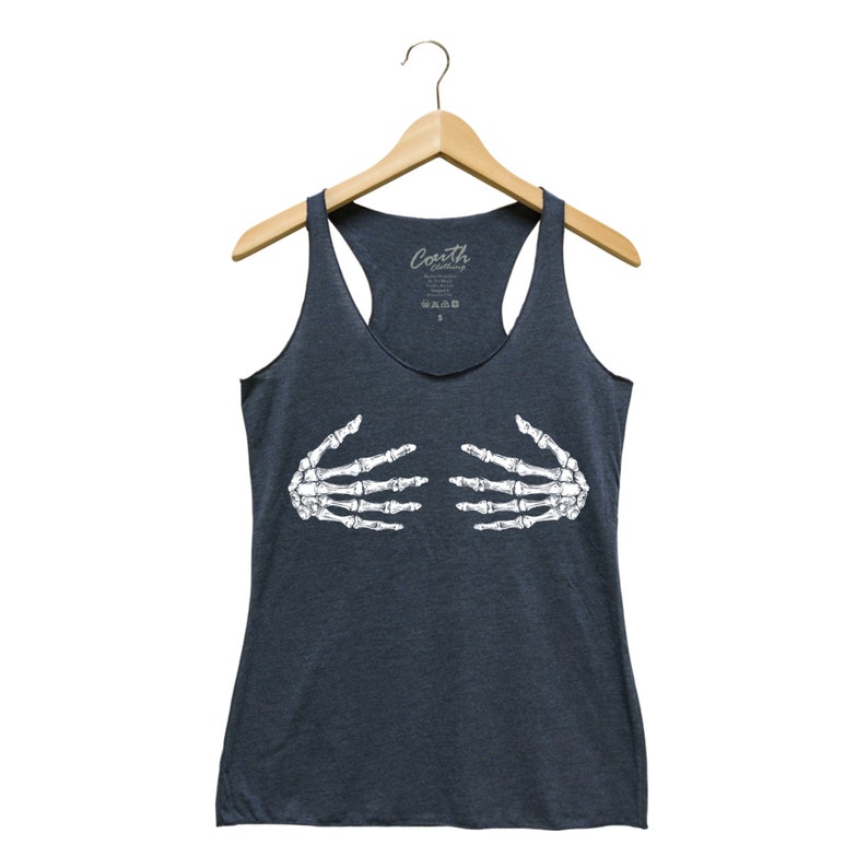 May include: Dark gray tank top with a white skeleton hand graphic. The tank top has a racerback design and a scoop neck. The brand name "Couth Clothing" is printed on the top. The tank top is hanging on a wooden hanger.