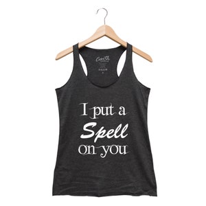 Puede incluir: Un top de tirantes gris oscuro con el texto "I put a spell on you" en blanco.