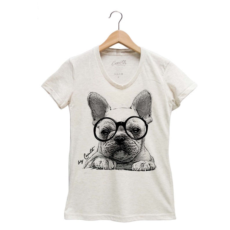 K&ouml;nnte beinhalten: Ein wei&szlig;es T-Shirt mit einer Schwarzwei&szlig;illustration eines franz&ouml;sischen Bulldoggen, der eine runde Brille tr&auml;gt. Der Text "by Coult" ist auf dem Shirt aufgedruckt.