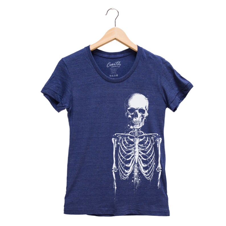 Puede incluir: Una camiseta azul marino con un gr&aacute;fico de esqueleto blanco. El esqueleto est&aacute; de pie con los brazos a los lados. El cr&aacute;neo es visible en la parte superior del esqueleto.