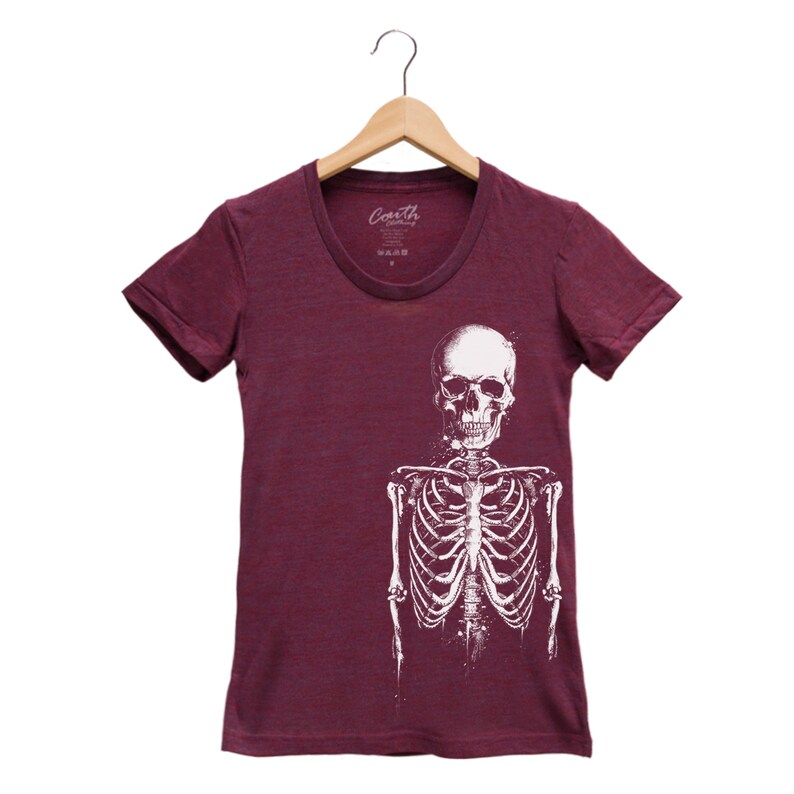 Puede incluir: Una camiseta de color granate con un gr&aacute;fico de esqueleto blanco. El esqueleto est&aacute; de frente con los brazos a los lados. La camiseta tiene un cuello redondo.