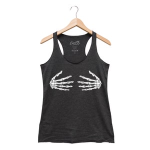 May include: Dark gray racerback tank top featuring a white skeleton hand graphic. The tank top is hanging on a wooden hanger. The brand name "Couth Clothing" is printed on the tag.