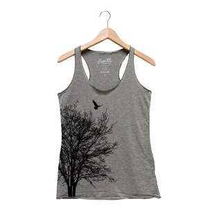 Könnte beinhalten: Ein graues Tanktop mit einer schwarzen Silhouette eines Baumes und einem Vogel, der darüber fliegt. Der Text "South Clothing" ist auf dem Oberteil aufgedruckt.