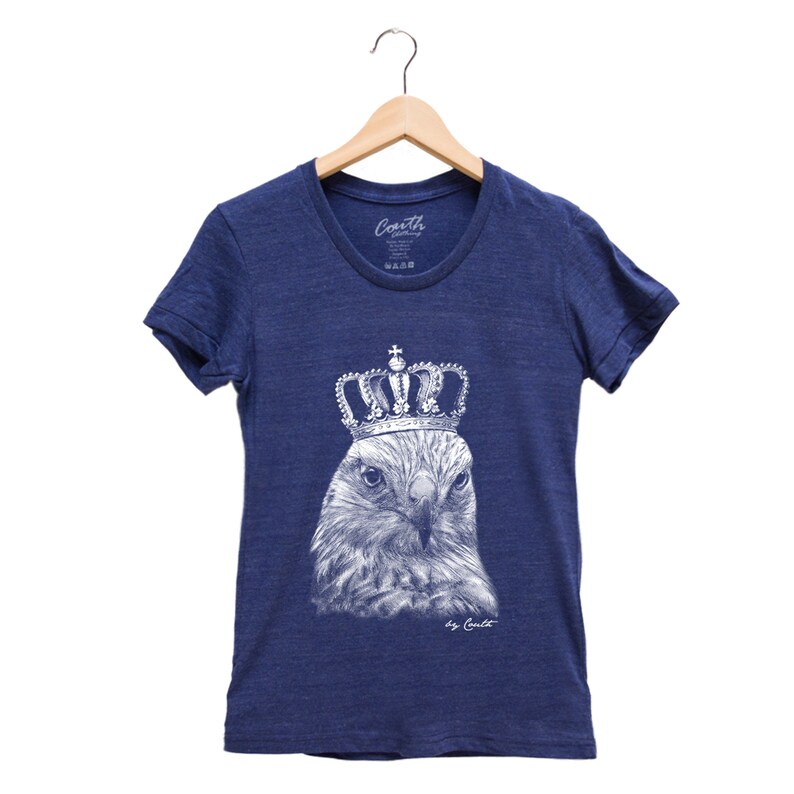 May include: A navy blue t-shirt with a white graphic of a hawk wearing a gold crown. The text "by Coult" is printed below the graphic.