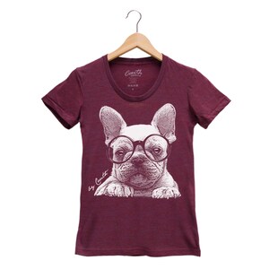 K&ouml;nnte beinhalten: Burgunderfarbenes T-Shirt mit einer wei&szlig;en Grafik eines franz&ouml;sischen Bulldoggen, der eine runde Brille tr&auml;gt. Der Text "by Coyutt" ist unter dem Bild gedruckt.