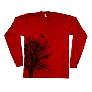 May include: Red long-sleeved t-shirt featuring a black silhouette of a tree and a bird in flight above it.