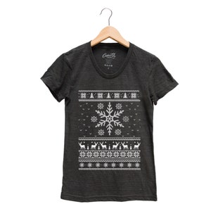 May include: A dark gray t-shirt with a white snowflake and reindeer pattern. The shirt has a crew neck and short sleeves. The text "Coath" is visible on the tag.