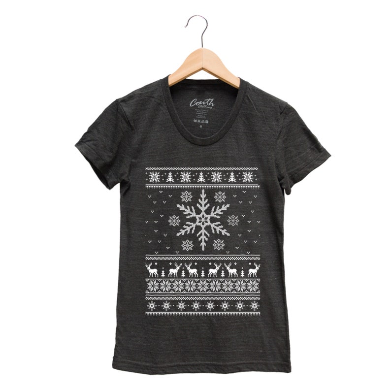 May include: A dark gray t-shirt with a white snowflake and reindeer pattern. The shirt has a crew neck and short sleeves. The text "Coath" is visible on the tag.