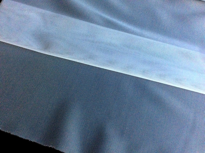 May include: A close-up of two pieces of fabric. The top piece is a light blue sheer fabric with a subtle ribbed texture. The bottom piece is a dark blue fabric with a fine, vertical ribbed texture.