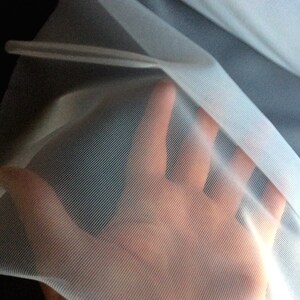 May include: White sheer fabric with a fine mesh texture. The fabric is translucent and has a soft, delicate feel.