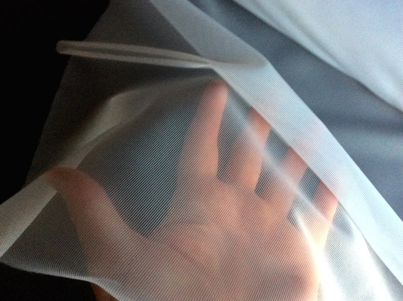 May include: White sheer fabric with a fine mesh texture. The fabric is translucent and has a soft, delicate feel.