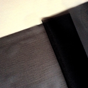 Puede incluir: Dos piezas de tela negra con textura tejida. La tela está doblada, mostrando los diferentes tonos de negro.