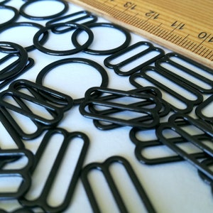 May include: A collection of black metal slider buckles, also known as slider clasps, for crafting projects. These buckles are commonly used for straps, bags, and other DIY projects.