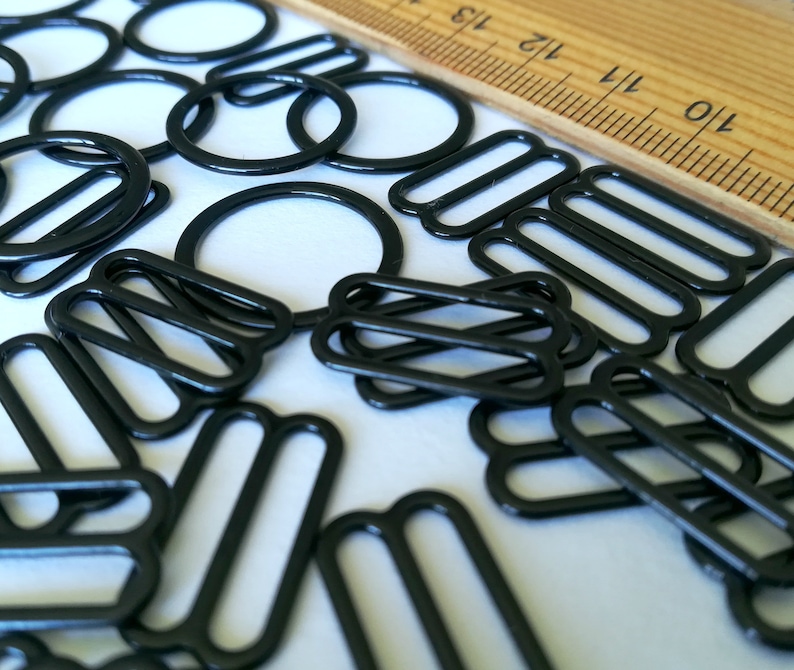 May include: A collection of black metal slider buckles, also known as slider clasps, for crafting projects. These buckles are commonly used for straps, bags, and other DIY projects.