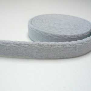 May include: A roll of light blue cotton webbing with a slightly textured surface.