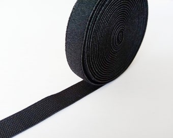 Puede incluir: Un rollo de tela elástica negra, ideal para proyectos de costura. La tela está enrollada apretadamente y tiene una superficie texturizada.