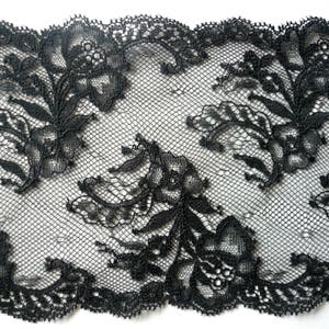 Puede incluir: Borde de encaje negro con un patrón floral. El encaje tiene un borde festoneado.