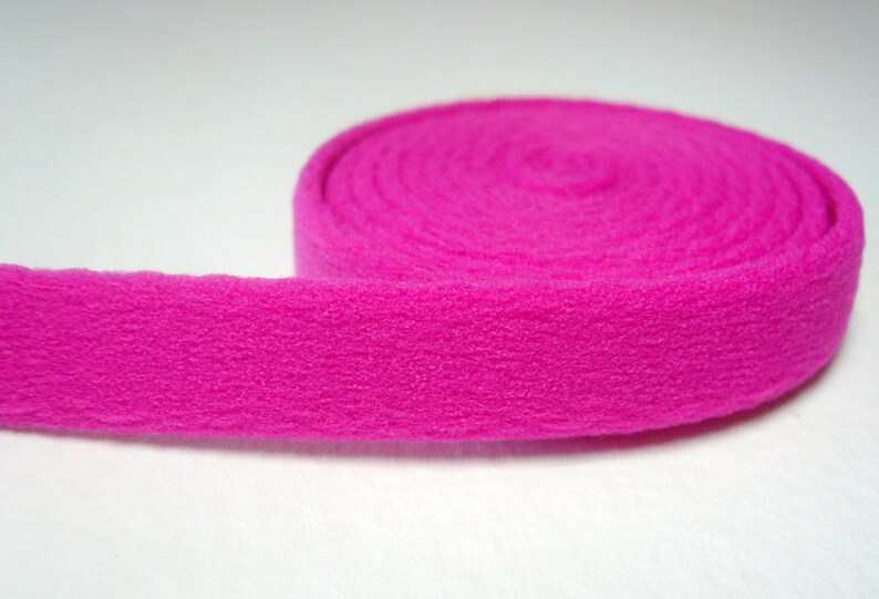 May include: A roll of bright pink fleece fabric. The fabric is soft and fuzzy, and it is perfect for crafting projects.