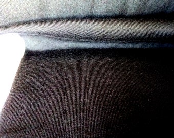 May include: Close-up of a black fabric with a textured surface. The fabric is folded in half, showing the inside of the fabric.
